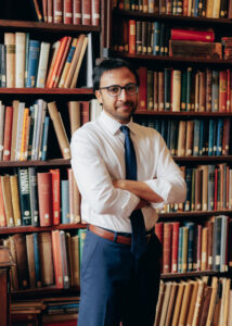 Nikhil Goyal standing in front of a wall of books